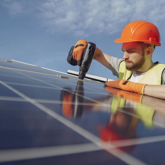 Handwerker mit Helm installiert Solarmodul – NPB connect für echte Aufträge ohne Kaltakquise